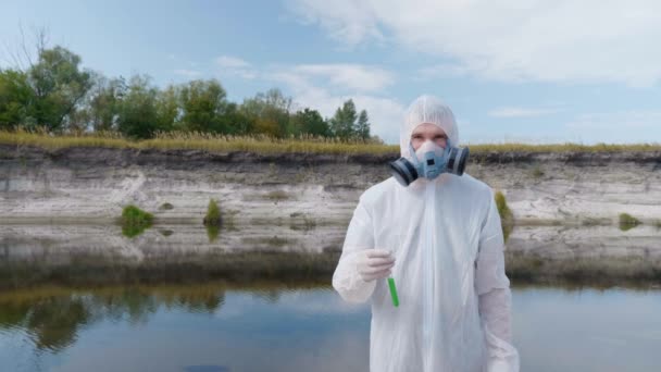 Man Skyddande Dräkt Och Gasmask Andningsskydd Står Med Ett Provrör — Stockvideo
