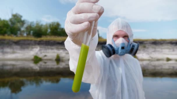 Muž Ochranném Obleku Respirátoru Ukazuje Zkumavku Analýzou Vody Znečištěné Řeky — Stock video