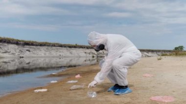 Koruyucu giysili ve solunum cihazı giyen adam yerden atılan plastik çöpleri alır ve çok kötü olduğunu gösterir. Belirtilmeyen yerlere çöp atmayın. Ekolojik felaket gezegen 4k kaydedin