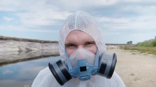 防護服と人工呼吸器を着た男がカメラを不審に見える 環境汚染問題の概念生態学的災害人為的影響惑星を保存します クローズアップ4K映像 — ストック動画