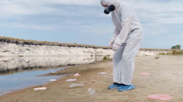 Człowiek Kombinezon Ochronny Respirator Odbiera Wyrzucić Plastikowe Śmieci Ziemi Pokazuje — Wideo stockowe