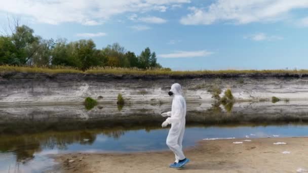 防護服と人工呼吸器を着た男性が乾いた川を歩き 汚染の程度を推定する 人類は地球を汚染している生態学的な大きなトロフィー人為的影響4K — ストック動画