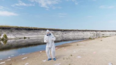 Vitro ile koruyucu bir takım elbise ve solunum adam kurutulmuş ve kirli nehir, göl tarafından popüler bir dans gerçekleştirir. Çevre kirliliği sorunu kavramı. Ekolojik felaket. Antropojenik etki. 4k