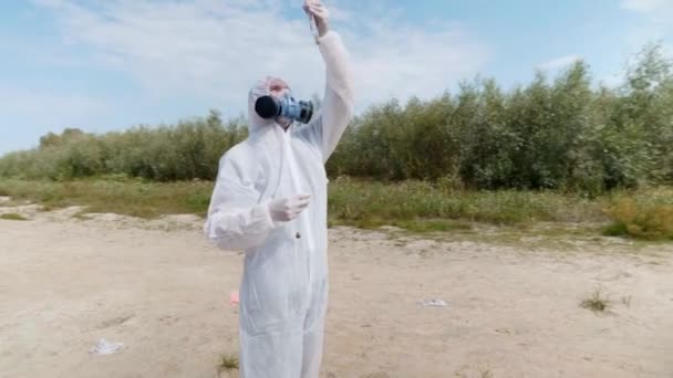 보호복과 호흡보호구를 착용한 남자는 시험관에서 반응을 관찰하고 오염된 강에서 분석을 — 비디오