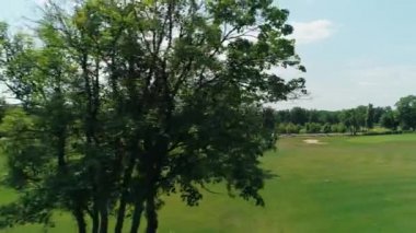 Güzel ağaçlar ve orman, yaz aylarında güneşli bir günde bulutlar ile mavi gökyüzü ile yeşil bir golf sahası havadan görünümü. 4k drone görüntüleri.