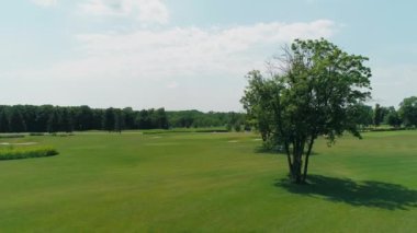 Güzel ağaçlar ve orman, yaz aylarında güneşli bir günde bulutlar ile mavi gökyüzü ile yeşil bir golf sahası havadan görünümü. 4k drone görüntüleri.