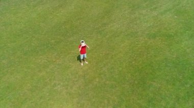 Parkta kafasına Vr kulaklık atan adamın havadan görüntüsü. Kasklı genç adam doğanın arka planında artırılmış gerçeklik yaşıyor. 4k drone görüntüleri.