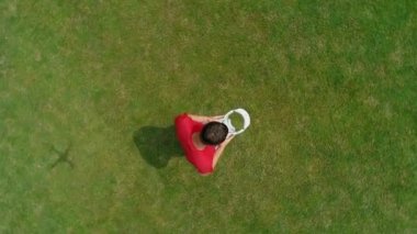 Parkta kafasına Vr kulaklık atan adamın havadan görüntüsü. Kasklı genç adam doğanın arka planında artırılmış gerçeklik yaşıyor. 4k drone görüntüleri.