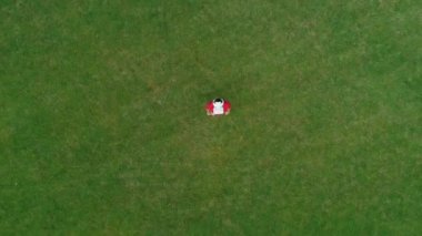 Kafasında Vr kulaklığı olan ve parktaki kameraya bakan adamın havadan görüntüsü. Kasklı genç adam doğanın arka planında artırılmış gerçeklik yaşıyor. 4k drone görüntüleri.