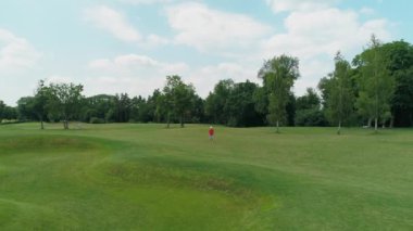 Güzel ağaçlar ve ormanlar arasında yeşil çimenler üzerinde duran, yaz aylarında güneşli bir günde bulutlarla mavi gökyüzü, kafasında sanal gerçeklik kulaklığı olan adamın havadan görünümü. 4k drone görüntüleri.