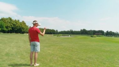 Kafasında sanal gerçeklik kulaklığı olan bir adam ayakta ve güzel orman arasında yeşil çim üzerinde Vr kask kullanarak, yaz aylarında güneşli bir günde bulutlar ile mavi gökyüzü. 4k drone görüntüleri.