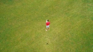 Vr kulaklığı takmaya başlayan ve parkta sanal bir oyun oynamaya başlayan adamın havadan görünümü. Kasklı genç adam doğanın arka planında artırılmış gerçeklik yaşıyor. 4k drone görüntüleri.