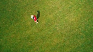 Vr kulaklık kullanan ve parkta sanal bir oyun oynayan adamın havadan görünümü. Kasklı genç adam doğanın arka planında artırılmış gerçeklik yaşıyor. 4k drone görüntüleri.