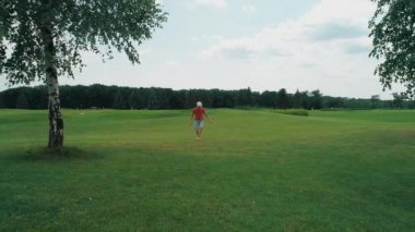 Vr kulaklık kullanan ve parkta sanal bir oyun oynayan bir adam. Kasklı genç adam doğanın arka planında artırılmış gerçeklik yaşıyor. Çerçevenin sağ tarafında bir insan var. 4k drone görüntüleri.