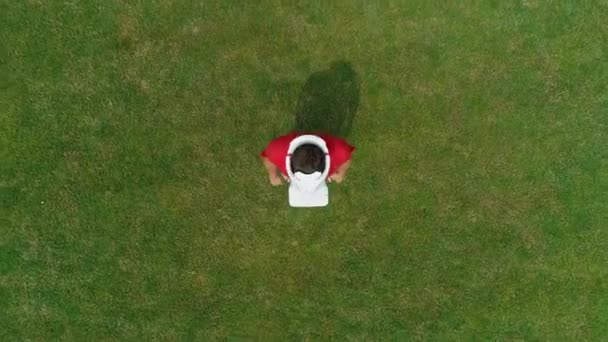 Vue aérienne de l'homme avec un casque VR sur la tête, qui regarde la caméra dans le parc. Jeune homme en casque expérimentant la réalité augmentée sur le fond de la nature. Images de drone 4K .