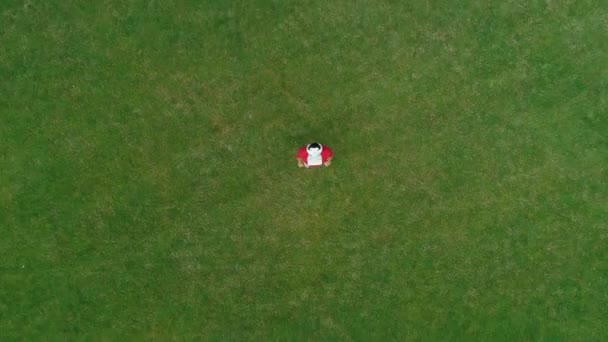 Vue aérienne de l'homme avec un casque VR sur la tête, qui regarde la caméra dans le parc. Jeune homme en casque expérimentant la réalité augmentée sur le fond de la nature. Images de drone 4K .