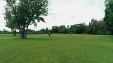 Vr kulaklık kullanan ve parkta sanal bir oyun oynayan bir adam. Kasklı genç adam doğanın arka planında artırılmış gerçeklik yaşıyor. Çerçevenin sağ tarafında bir insan var. 4k drone görüntüleri.