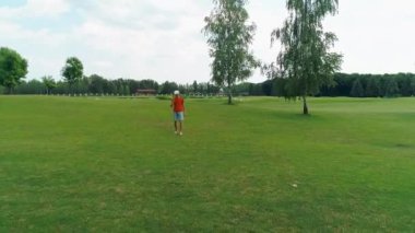 Vr kulaklık kullanan ve parkta sanal bir oyun oynayan bir adam. Kasklı genç adam doğanın arka planında artırılmış gerçeklik yaşıyor. Çerçevenin sağ tarafında bir insan var. 4k drone görüntüleri.