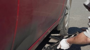Beyaz eldivenli tecrübesiz bir adam kırık ve kirli kırmızı bir arabayı çalmaya çalışıyor. Genç adam dışarıda oto tamir ediyor. Otomobil yolda bozuldu. Close. 4k görüntü.