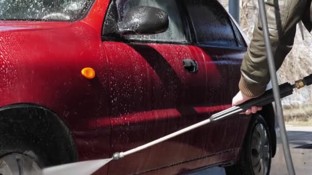 男人在自助洗车时洗车 高压的喷水冲走了汽车的污垢 泡沫洗涤剂从汽车引擎盖排出 — 图库视频影像