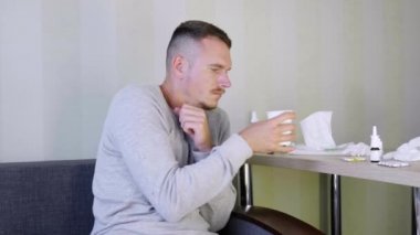 Hasta adam evde kendi kendine ilaç kullanıyor. Üzgün genç adam donuyor ve kağıt bardak sıcak çay ile sıcak tutmaya çalışır. Başucunda bir sürü ilaç var. Akut Solunum Yolu Virüsü Enfeksiyonu. Hastalık soğuk algınlığı.