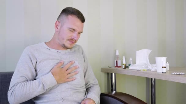 病人在家自我治疗 心烦意乱的小伙子坚持到胸部 因为肺部受伤 床头柜上有很多药物 急性呼吸道病毒感染 感冒病4K — 图库视频影像