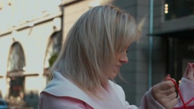 Kırmızı kağıt torba içinde hediye, üzgün pembe ceketli genç çekici sarışın kadının portre çekimi. Umut ve hayal kırıklığı. Noel tatilleri, satış ve perakende sektörü konsepti. 4k görüntü.