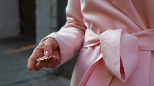 ピンクのコートを着た若い魅力的な女性は 暗号通貨の買い物をしています ビットコインの金貨を持つ通りの女性のクローズアップビュー クリスマス休暇 小売業界のコンセプト 4Kフッテージ — ストック動画