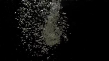 Sayısız küçük hava kabarcıkları kristal berrak suyun altına nüfuz ediyor, karıştırıyor ve yükseliyor, siyah arkaplanda fotokopi uzayı ile yavaşça dalgalanıyor. Sualtı baloncukları kargaşa çıkarıyor. Ağır çekim. Yakın plan.