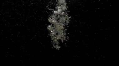 Sayısız küçük hava kabarcıkları kristal berrak suyun altına nüfuz ediyor, karıştırıyor ve yükseliyor, siyah arkaplanda fotokopi uzayı ile yavaşça dalgalanıyor. Sualtı baloncukları kargaşa çıkarıyor. Ağır çekim. Yakın plan.