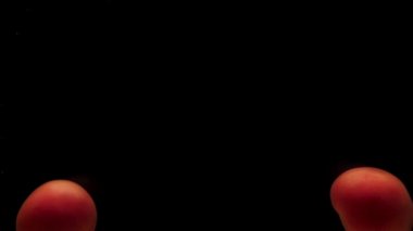 Siyah zemin üzerinde saydam suyun altında iki kırmızı domates yatıyor. Akvaryuma taze organik sebzeler sıçrıyor. Market, sağlıklı yiyecekler, diyet, vejetaryenlik, hava kabarcıkları. Ağır çekim. Yakın plan.