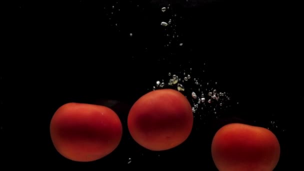 Drei Rote Tomaten Die Transparentes Wasser Auf Schwarzem Hintergrund Fallen — Stockvideo