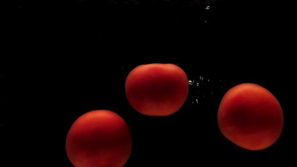 Drei Rote Tomaten Die Transparentes Wasser Auf Schwarzem Hintergrund Fallen — Stockvideo