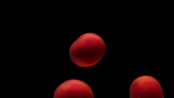 Drei Rote Tomaten Liegen Unter Transparentem Wasser Auf Schwarzem Grund — Stockvideo