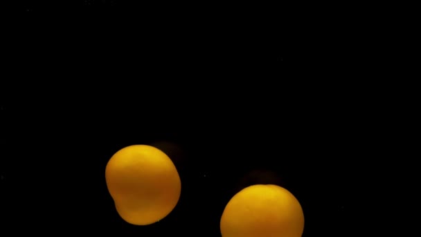 Twee Gele Tomaten Vallen Transparant Water Zwarte Achtergrond Verse Biologische — Stockvideo