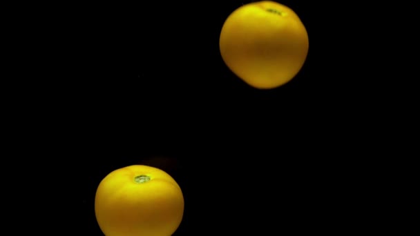 Δύο Κίτρινες Ντομάτες Πέφτουν Διάφανο Νερό Μαύρο Φόντο Φρέσκα Βιολογικά — Αρχείο Βίντεο