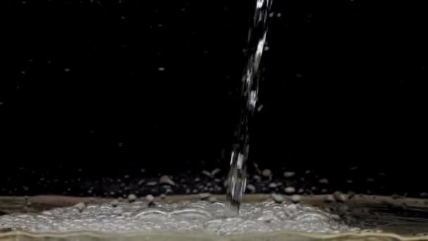 黒い背景に水の流れが落ちる クリスタルクリア水の流れは 表面にヒットし コピースペースと気泡を作成します スローモーション — ストック動画