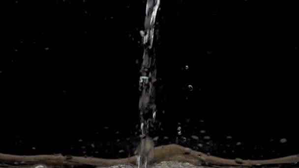 黒い背景に水の流れが落ちる クリスタルクリア水の流れは 表面にヒットし コピースペースで飛ぶスプラッシュ スローモーション — ストック動画