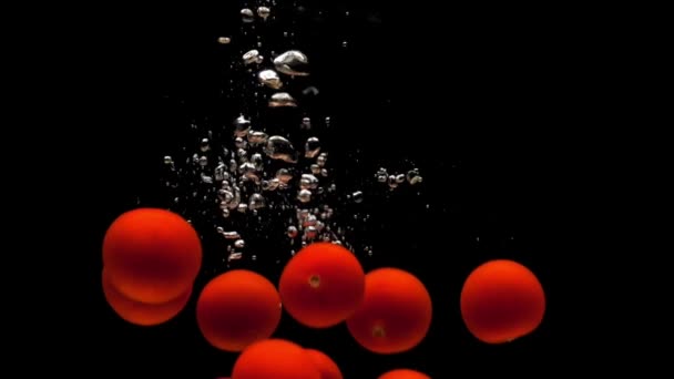 Красные Помидоры Черри Падают Прозрачную Воду Черном Фоне Свежие Органические — стоковое видео