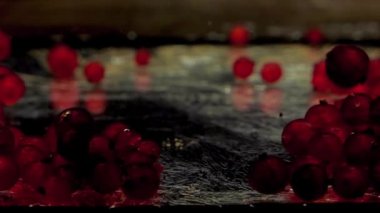 Yeşil kepçe kırmızı frenk üzümlerini yakalar ve siyah zemin üzerinde şeffaf suda yukarı çeker. Akvaryumda taze organik meyveler. Market, sağlıklı yiyecekler, vejetaryenlik. Ağır çekim. Yakın plan..