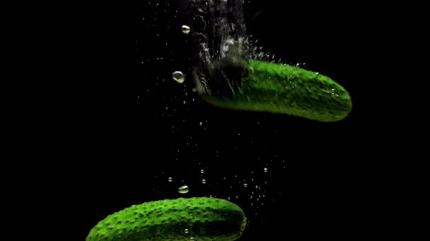 绿色的黄瓜在黑色的背景上掉进透明的水里 新鲜的有机蔬菜在水族馆里飞溅 杂货店 健康食品 空气泡泡 慢动作 后续行动 — 图库视频影像