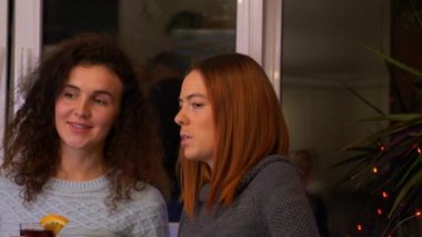 Ellerinde bir bardak sıcak şarapla kızlar şenlik partisinde iletişim kurarlar. Yılbaşı partisini evde kutlayan iki genç kadın. Mutlu arkadaşlar birlikte. Tatiller ve kutlama konsepti. 4k