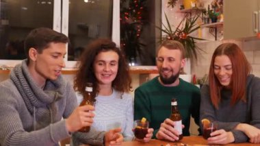 Mutlu arkadaşlar kadeh tokuşturup yeni yıl partisini evde kutluyorlar. Pizza, bira şişeleri ve masada sıcak şarap. Tatiller ve kutlama konsepti. 4k görüntü.