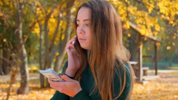 Ung Attraktiv Brunette Kvinde Taler Telefon Holder Pakke Penge Pigen – Stock-video