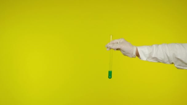 Hand in latex glove protection shows a glass tube with the green substance — Stock Video