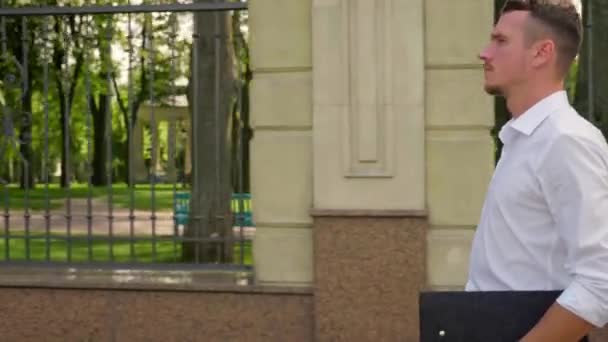 Geschäftsmann mit Laptop in der Hand läuft durch den Park und schaut sich um — Stockvideo