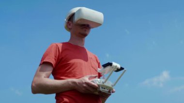 Adam bir kuadrokopteri uzaktan kumandayla kontrol ediyor.