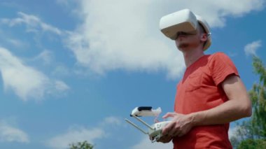 Adam bir kuadrokopteri uzaktan kumandayla kontrol ediyor.