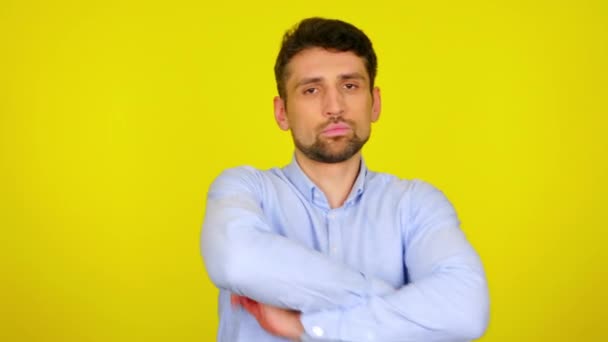 Mann wendet sich der Kamera zu, verschränkt die Arme und schüttelt vor gelbem Hintergrund den Kopf — Stockvideo