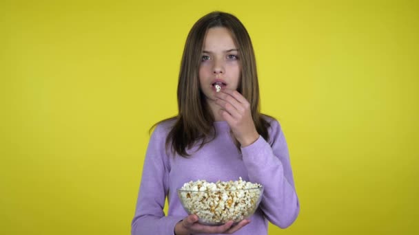 Tiener meisje eet popcorn uit een glazen kom en is ongelukkig met de smaak — Stockvideo